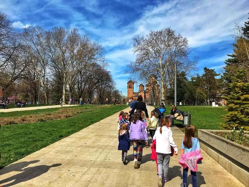 Grupa dece u prolećnoj šetnji kroz park kod Vukovog spomenika u Beogradu
